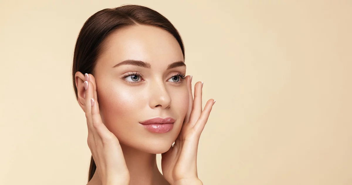 Woman with glowing skin touching face after Diamond Glow Facial In Ames, IA